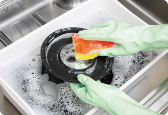 汁受け皿や五徳などは台所用中性洗剤を溶かしたぬるま湯に浸けてしばらく置き、スポンジ等でこすります